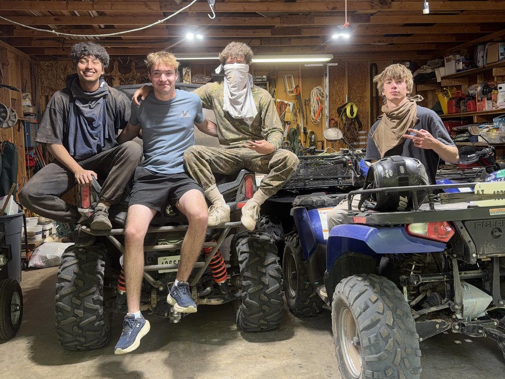Shash with friends sitting on an ATV in a garage